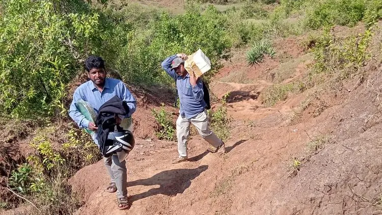 2 men carrying supplies up a hillside