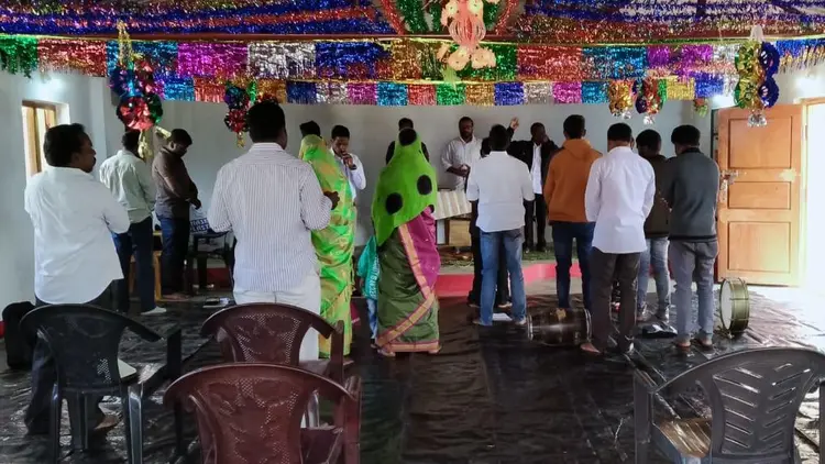 group of people standing to pray at public meeting